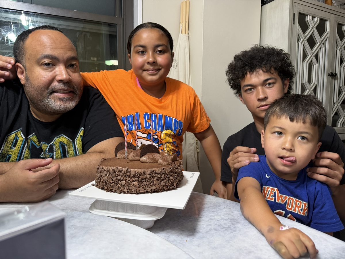 Dad and the kids smiling around a chocolate birthday cake